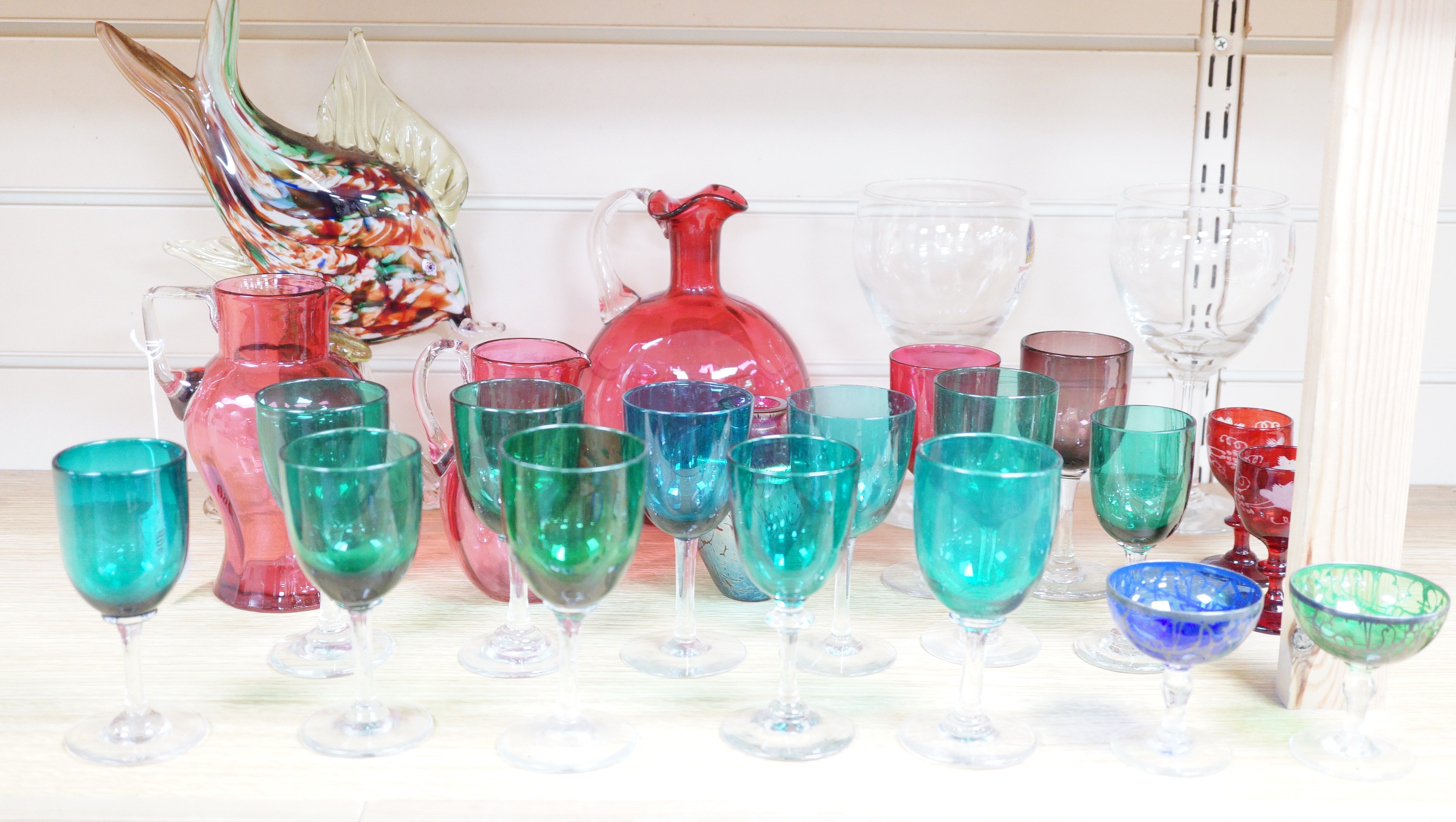 A quantity of cranberry glass, together with other coloured glassware and a Murano style fish ornament